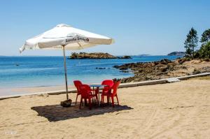 una mesa y sillas bajo una sombrilla en la playa en Contemporary Apartment in Riveira + Sea View, en Ribeira