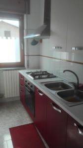 a kitchen with red cabinets and a stove and a sink at One bedroom apartement with wifi at Calvello in Calvello