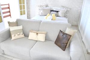 una sala de estar con un sofá blanco con almohadas en Studio avec vue sur la ville balcon et wifi a Baie Mahault, en Baie-Mahault
