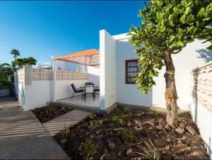 a white house with a table and a tree at Charming Bungalow in Maspalomas with Shared Pool in Maspalomas