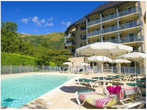 a hotel with a swimming pool with chairs and umbrellas at Appartement de 2 chambres a Saint Lary Soulan a 100 m des pistes avec piscine partagee et jardin amenage in Saint-Lary-Soulan