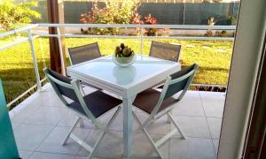 a white table with chairs and a bowl of fruit on a balcony at Bungalow charmant à Sainte-Anne in Sainte-Anne