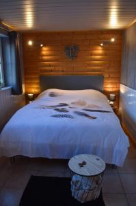 1 dormitorio con cama blanca y pared de madera en Gîte du cheval blanc d'Houmont, en Sainte-Ode