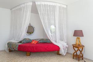 Un dormitorio con una cama roja con cortinas y una ventana en Villa de 2 chambres avec vue sur la mer piscine privee et jardin clos a Sainte Rose, en Sainte-Rose