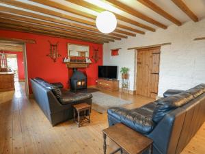 a living room with leather furniture and a fireplace at The Farmhouse in Ciliau-Aeron