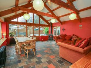 - un salon avec des murs rouges, une table et des chaises dans l'établissement The Farmhouse, à Ciliau-Aeron