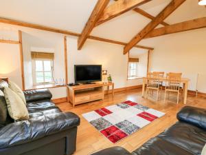 a living room with leather furniture and a flat screen tv at The Stable in Lampeter