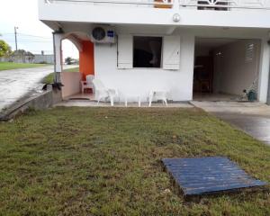 une maison blanche dotée de chaises et d'une pelouse. dans l'établissement Studio tout confort à Sainte-Anne - 39 m² - Vue sur jardin, à Sainte-Anne 4 autres photos