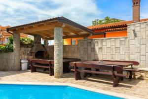 um pátio com uma mesa de piquenique, comodidades para churrascos e uma piscina em Villa Marko em Medulin