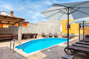 uma piscina com um guarda-sol e cadeiras e uma mesa em Villa Marko em Medulin