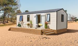 une petite maison assise sur un champ de terre dans l'établissement Camping Campéole Plage Sud - Maeva, à Biscarrosse