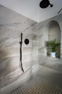 um chuveiro na casa de banho com paredes em mármore branco em Daya - Old City Acre em Acre