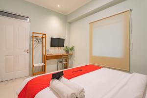 a bedroom with a bed and a desk and a television at RedDoorz Plus @ Bagusrangin Street in Bandung