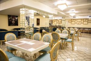 um restaurante com mesas e cadeiras num quarto em VELARA HOTEL em Tashkent