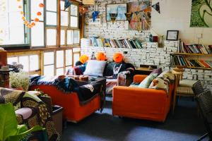 a room with three people sitting on orange chairs at Backpacker Village Hostel in Xiamen