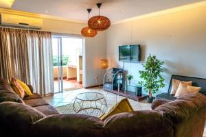 Una sala de estar con un sofá y un televisor. en L'escalier Cabanas 107, en Amanzimtoti