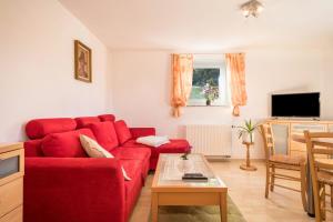 a living room with a red couch and a table at Ferienwohnung Marschall in Achberg