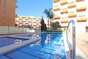 a swimming pool in front of a building at Global Properties, Apartamento en la playa de Canet d'en Berenguer in Canet de Berenguer