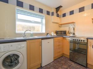 a kitchen with a washing machine and a sink at Whimple Cottage in Exeter