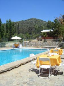 - une table et des chaises jaunes à côté de la piscine dans l'établissement El Parador de Caleu, à Tiltil