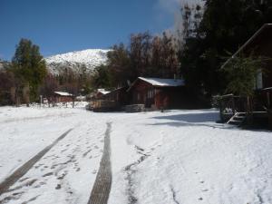 a snow covered road with a house and a mountain at El Parador de Caleu in Tiltil