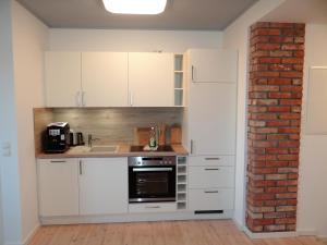 uma cozinha com armários brancos e uma parede de tijolos em Speicher Residenz Barth E1 App 5 em Barth