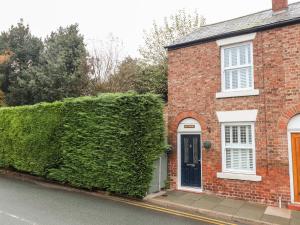 a red brick house with a green hedge at Elv Cottage in Chester