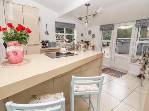 a kitchen with a counter with two chairs and a vase with roses at Elv Cottage in Chester