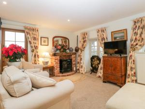 a living room with a fireplace and a tv at Colly Cottage in Bridport