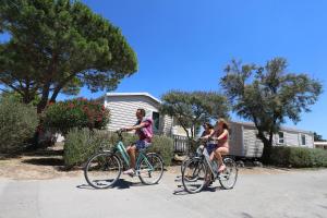 dwoje ludzi jeżdżących rowerami ulicą w obiekcie Camping Campéole La Côte des Roses - Maeva w mieście Narbona