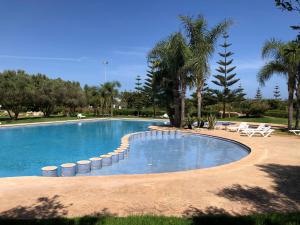 una grande piscina con sedie e palme di Appt Bouznika EDEN ISLAND pied sur Mer a Bouznika