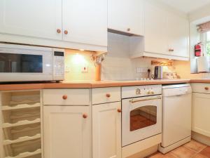 a kitchen with white cabinets and a microwave at Spring Cottage in Cirencester