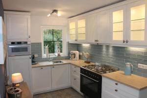 a kitchen with white cabinets and a stove top oven at Strandperle 83 in Julianadorp