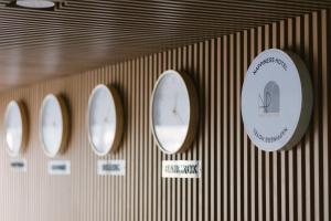 a wall with three clocks and a sign on it at Nappiness Hotel - SHA ExtraPlus in Bangkok