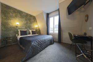 a bedroom with a bed and a desk and a window at Hôtel Azur in Reims