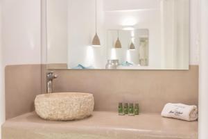 a white sink sitting under a mirror in a bathroom at Anna Platanou Suites in Agia Irini Paros