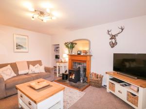 a living room with a couch and a fireplace at Stonywood Cottage in Drumnadrochit