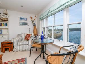 ein Wohnzimmer mit Tisch und Stühlen und Fenstern in der Unterkunft Pier Cottage in Saint Mawes