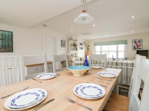 a dining room with a wooden table with plates on it at Pier Cottage in Saint Mawes