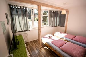 two beds in a room with two windows at Black Forest Bike Hostel in Kirchzarten