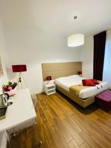 a bedroom with a bed and wooden floors and a table at Mapi’s Rooms in Cagliari