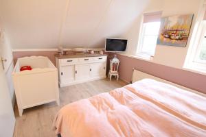 a bedroom with a bed and a desk with a tv at Strandperle 83 in Julianadorp