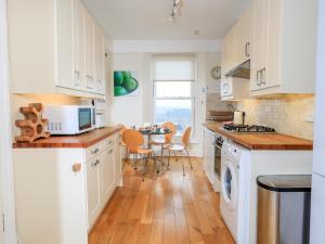 a kitchen with white cabinets and a table with chairs at 2 North Crest House in Salcombe