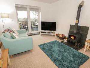 a living room with a blue couch and a fireplace at Hen Stabl in Llanrwst
