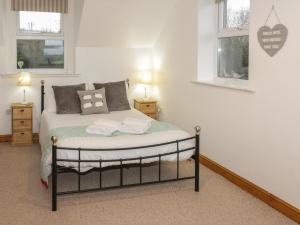 a bedroom with a bed and two windows at Hen Stabl in Llanrwst