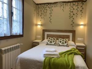 sypialnia z łóżkiem z zieloną pościelą i poduszkami w obiekcie Cumbres de los Picos Apartamento La Yedra w mieście Poo de Cabrales