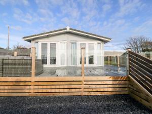 a house with a wooden fence in front of it at Caban Tywod in Pwllheli
