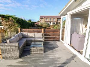 a patio with a couch and chairs on a balcony at Caban Tywod in Pwllheli