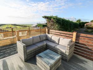 a couch sitting on top of a wooden deck at Caban Tywod in Pwllheli