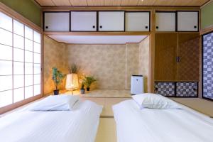 two beds in a room with windows at Villa RAKUWA Bettei in Fujikawaguchiko